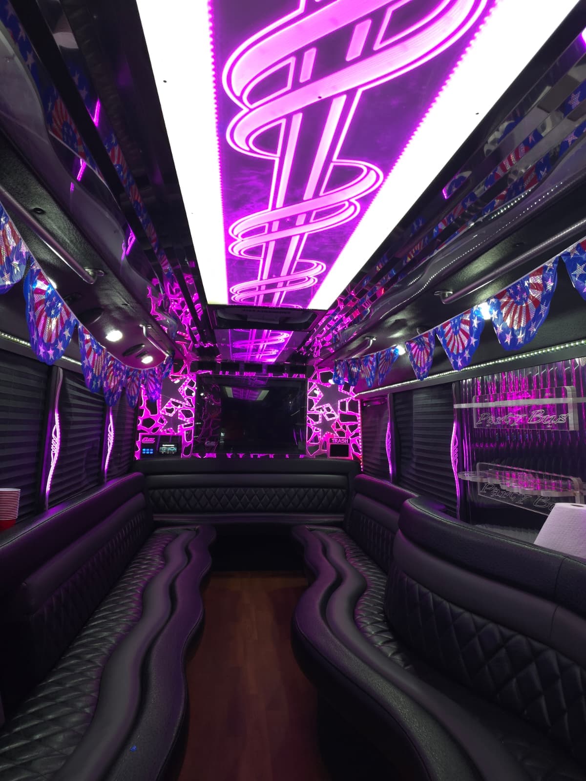 Interior of the El Khourys party bus, quilted black leather wraparound benches, hardwood aisle and coloured ceiling lighting