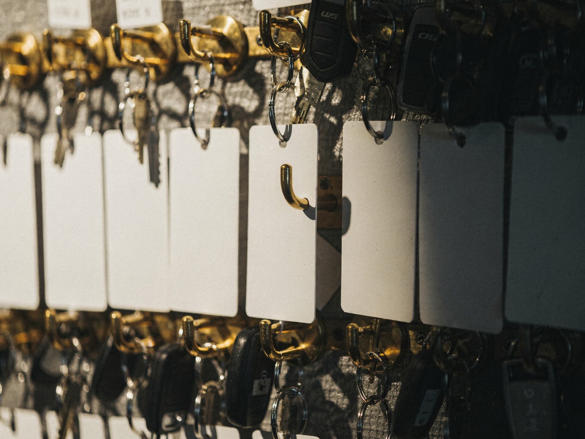 Close on a valet key board, numbered hooks with tagged fobs hanging from them and one hook empty.